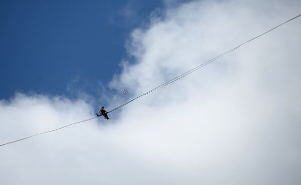 Канатоходец Максим Кагин во время прохода по стропе, натянутой на высоте 126 метров между двумя небоскребами жилого комплекса Чемпион Парк, в Екатеринбурге