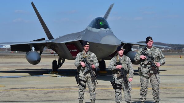Американские военнослужащие возле истребителя F-22 на базе ВВС США Осан в Пхентхэке, Южная Корея