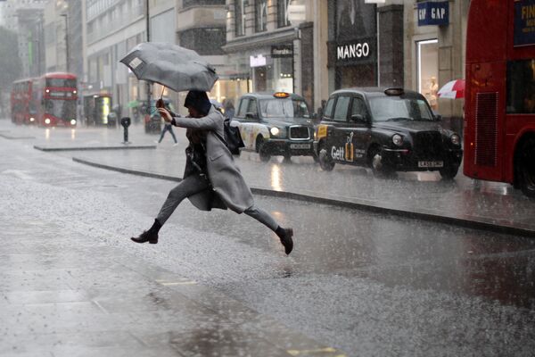 Девушка перепрыгивает лужу во время дождя в Лондоне. 9 августа 2017