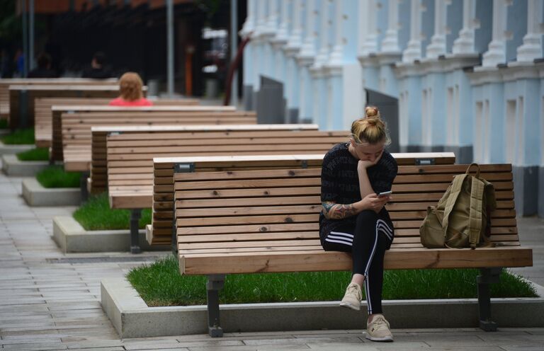 Девушка сидит на скамейке в 3-м Голутвинском переулке в Москве