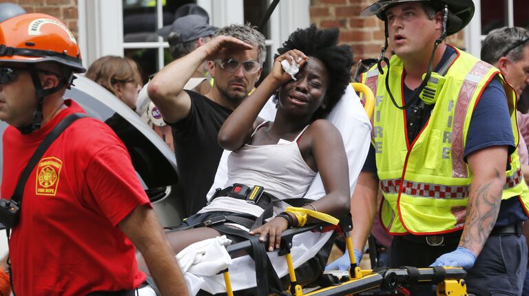 Спасатели оказывают женщине первую помощь после того, как автомобиль наехал на участников протестов в Шарлоттсвилле, штат Вирджиния