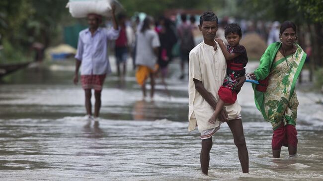 Люди во время наводнения в деревне Мурката к востоку от Гаухати в Индии