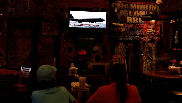 Местные жители смотрят новости в ресторане на острове Гуам, тихоокеанской территории США. 14 августа 2017 года