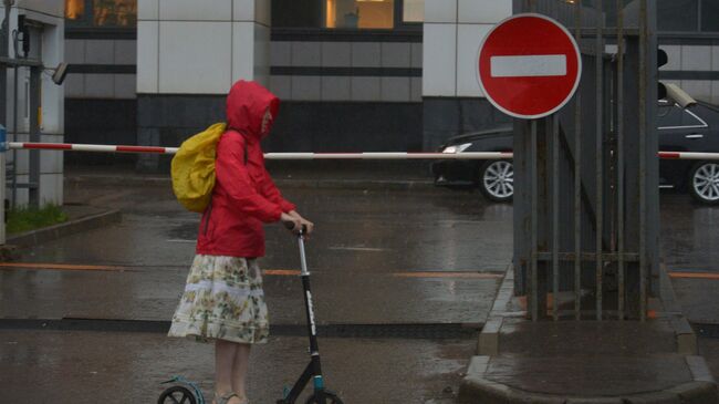 Девушка на самокате во время дождя в Москве