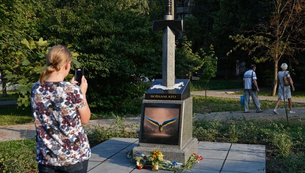 Женщина фотографирует памятник военным, погибшим на Донбассе, в Киеве. 15 августа 2017