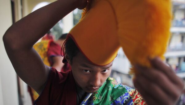Монах надевает головной убор перед торжественной церемонией в честь 25-летия вручения Нобелевской премии мира Далай-ламе. 10 декабря 2014