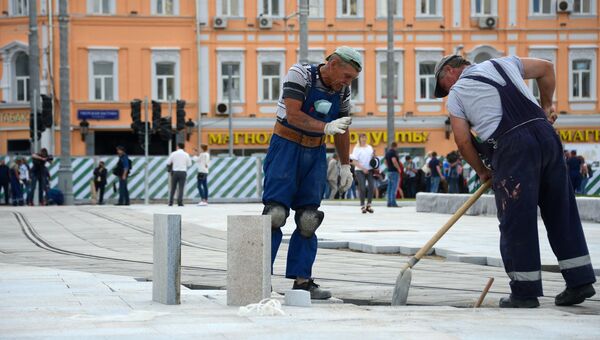 Рабочие кладут плитку на площади Тверская Застава в Москве. 17 августа 2017