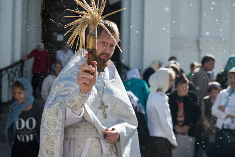 Священнослужитель окропляет святой водой яблоки и фрукты во время богослужения в честь праздника Преображения Господня у собора Воздвижения Креста Господня в Омске. 19 августа 2017