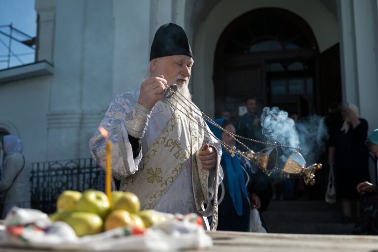 Священнослужитель и верующие во время богослужения в честь праздника Преображения Господня у собора Воздвижения Креста Господня в Омске. 19 августа 2017