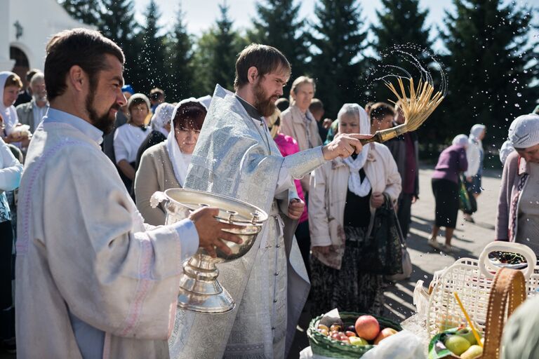 Священнослужитель окропляет святой водой яблоки и фрукты во время богослужения в честь праздника Преображения Господня у собора Воздвижения Креста Господня в Омске. 19 августа 2017