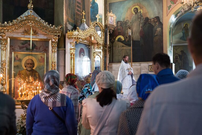 Священнослужитель и верующие во время богослужения в честь праздника Преображения Господня в соборе Воздвижения Креста Господня в Омске. 19 августа 2017