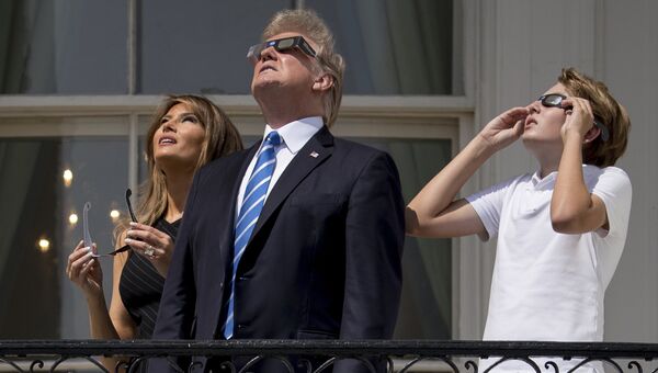 Дональд Трамп, Мелания Трамп и их сын Баррон Трамп смотрят на солнечное затмение. 21 августа 2017