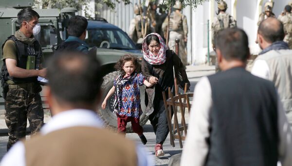 Женщина с ребенком убегают с места нападения на мечеть в Кабуле. 25 августа 2017
