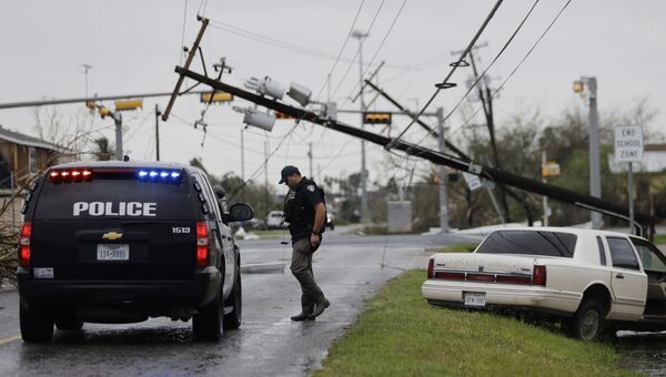 Полицейский проверяет заброшенный автомобиль после урагана Харви в Рокпорте, штат Техас. 26 августа 2017