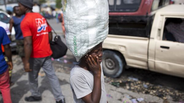 Мальчик носит воду, предназначенную для продажи, по улицам Порт-о-Пренс, Гаити. Архивное фото