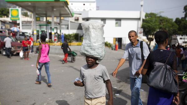 12-летний мальчик носит воду, предназначенную для продажи, по улицам Порт-о-Пренс, Гаити