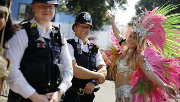 Участница ежегодного карнавал в лондонском районе Ноттинг-Хилл позирует с сотрудниками полиции
