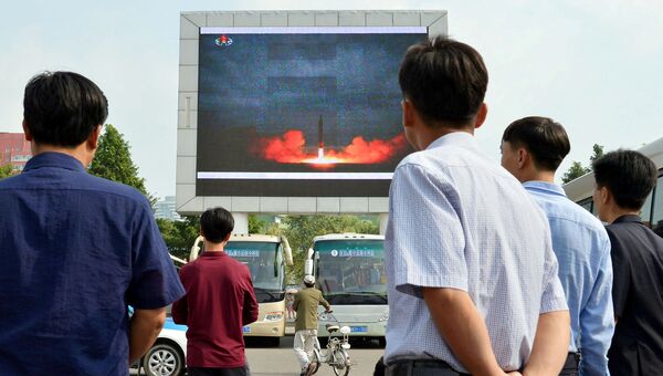 Жители КНДР смотрят репортаж о запуске баллистической ракеты Хвансон-12. 30 августа 2017