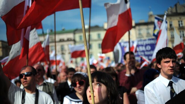 Жители Кракова с польскими флагами на площади города