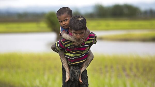 Мальчик из народности рохинджа несет на спине ребенка после перехода бангладешской границы. 1 сентября 2017