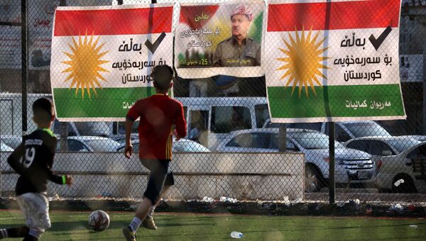 Дети играют в футбол на фоне плаката с изображением лидера иракских курдов Масуда Барзани в поддержку независимости на предстоящем референдуме в Арбиле. Архивное фото