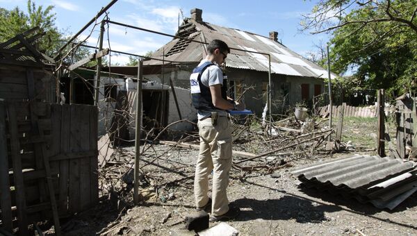Сотрудник ОБСЕ осматривает двор жилого дома, пострадавший в результате обстрела. Архивное фото