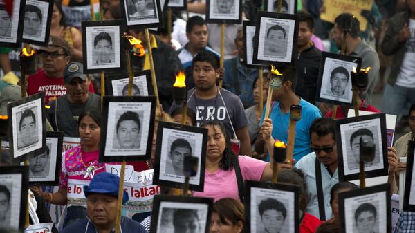 Члены семей и сторонники 43 пропавших студентов несут их фотографии во время марша в Мехико