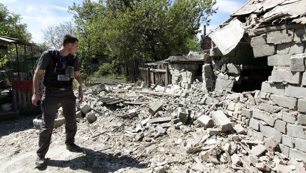 Сотрудник ОБСЕ осматривает двор жилого дома, пострадавший в результате обстрела Докучаевска в Донецкой области