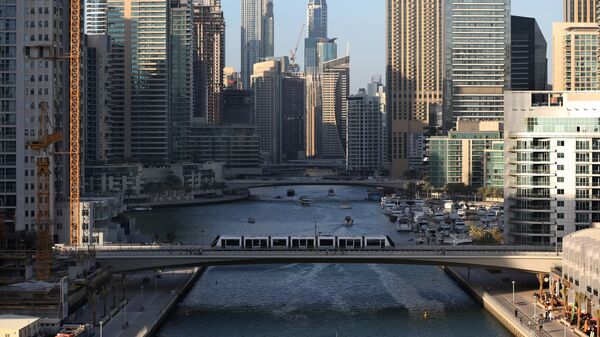 Трамвай проезжает по мосту через канал в Дубае