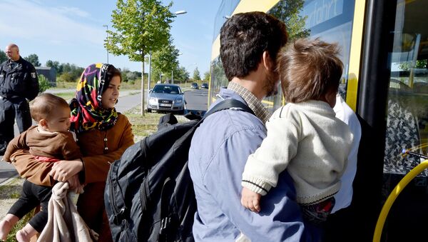 Семья мигрантов из Афганистана входит в автобус после прибытия на железнодорожную станцию Шенефельд, Германия