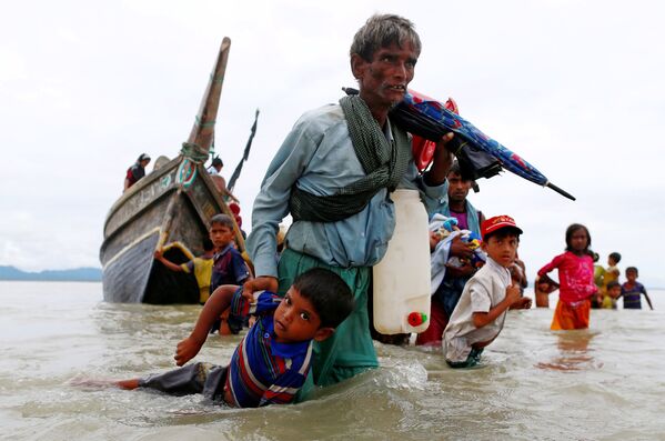Мужчина из народности рохинджа вытаскивает ребенка из воды после пересечения границы Бангладеш-Мьянма через Бенгальский залив