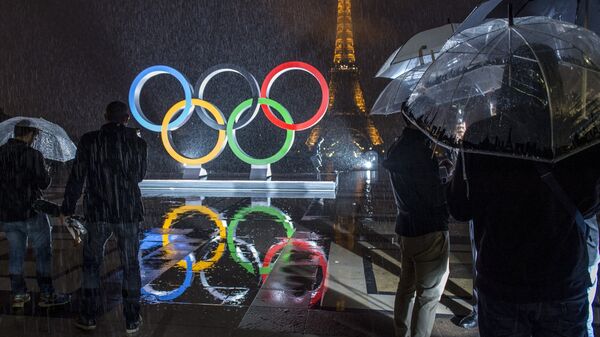 Туристы фотографируют Олимпийские Кольца на площади Трокадеро в Париже. Архивное фото