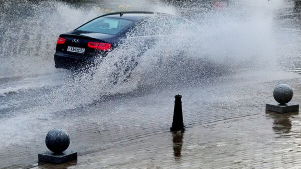Автомобиль едет по улице Москвы во время дождя
