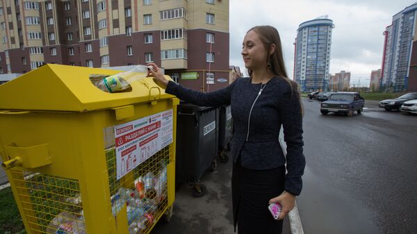 Студентка возле дома в Саранске выбрасывает бутылку в специальный контейнер для пластика. 