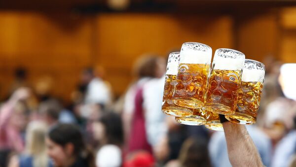 Официант несет кружки с пивом на открытии фестиваля Октоберфест в Мюнхене