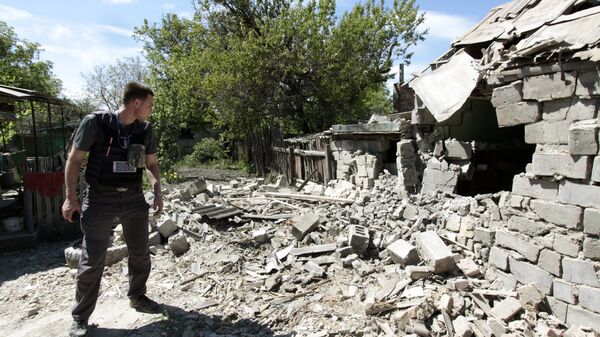 Сотрудник ОБСЕ осматривает двор жилого дома, пострадавший в результате обстрела в Донецкой области. Архивное фото