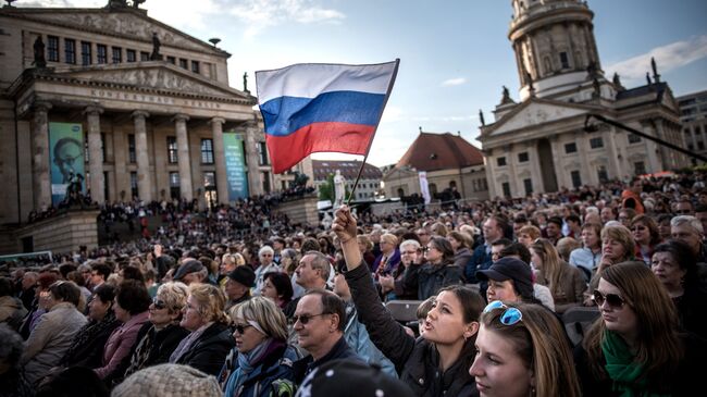 Посетители концерта Песни Победы на площади Жандарменмаркт в центре Берлина