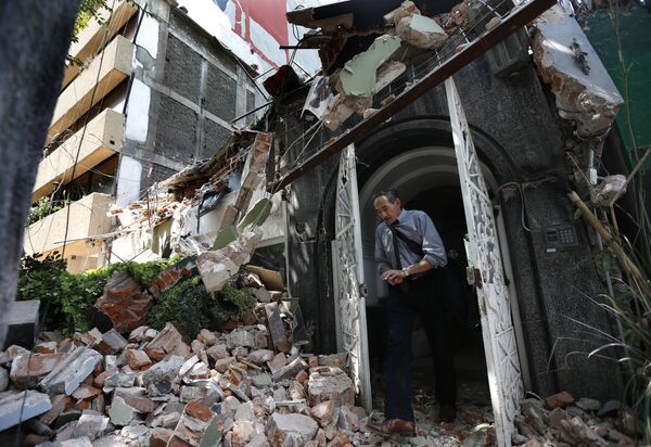 Мужчина выходит из здания, рухнушего после землетрясения, в Мехико. 19 сентября 2017