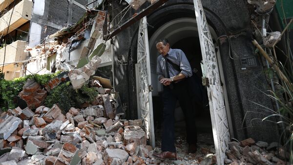 Мужчина выходит из здания, рухнушего после землетрясения, в Мехико. Архивное фото