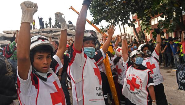 Спасатели просят тишины, чтобы услышать голоса возможных выживших под обломками здания, после землетрясения в Мехико. 19 сентября 2017