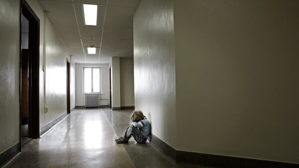 Расстроенный ребенок в пустом школьном коридоре. Архивное фото