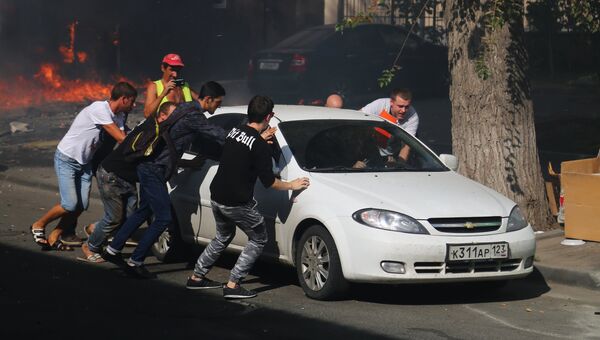 Мужчины отгоняют машину от горящего десятиэтажного здания в центре Ростова-на-Дону