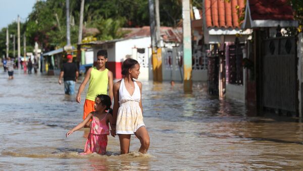 Люди гуляют по улице затопленной в результате разлива реки Юна, вышедшей из берегов после урагана Мария. 24 сентября 2017