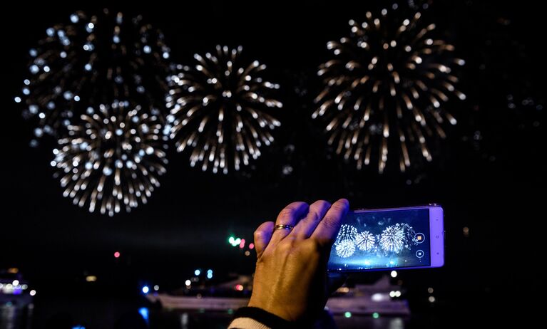 Посетительница фотографирует на мобильный телефон на церемонии закрытия 7-го Московского международного фестиваля Круг Света 2017 на Останкинском пруду в Москве