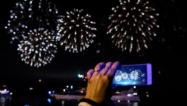 Посетительница фотографирует на мобильный телефон на церемонии закрытия 7-го Московского международного фестиваля Круг Света 2017 на Останкинском пруду в Москве