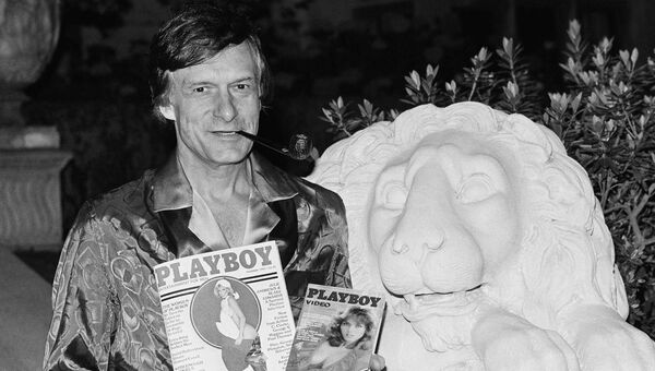 Хью Хефнер держит журнал Playboy и видеокассету с канала Playboy Channel во время интервью в особняке Playboy в Холмби-Хиллз. 29 ноября 1982