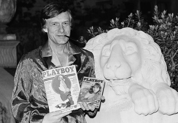 Хью Хефнер держит журнал Playboy и видеокассету с канала Playboy Channel во время интервью в особняке Playboy в Холмби-Хиллз. 29 ноября 1982