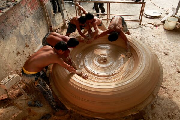 Рабочие лепят фарфоровый чан на заводе в Китае.