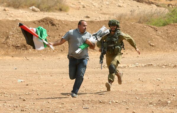 Израильский солдат бежит за палестинцем во время столкновений в городе Тубас на Западном берегу реки Иордан.