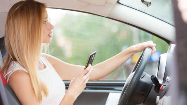 Девушка пользуется телефон за рулем автомобиля